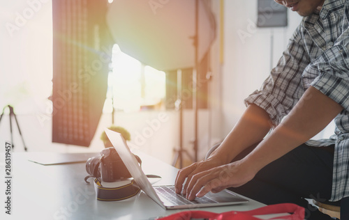 Young man sitting at desk editing images on computer. male photographer retouching photos in office using laptop.