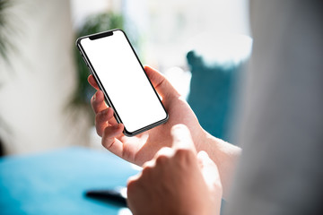 Man using smartphone blank screen frameless modern design while lying on the sofa in home interior