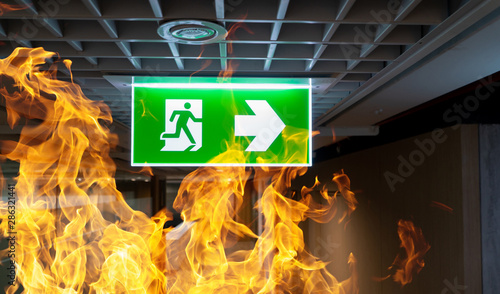Foto Green fire escape sign hang on the ceiling in the office.