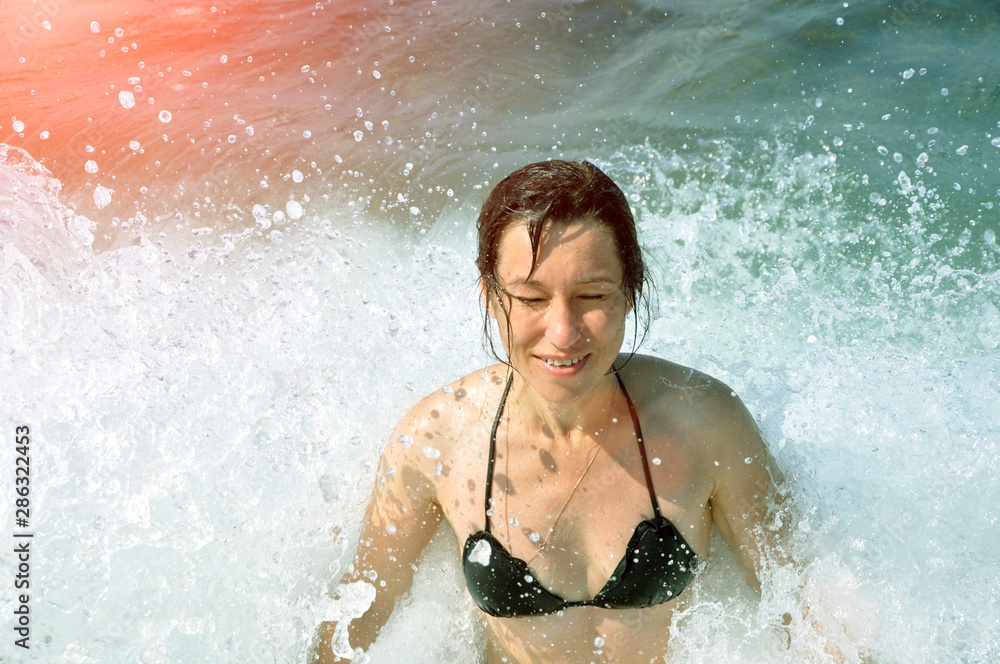 Obraz premium Beautiful young woman. In the spray of the sea wave.