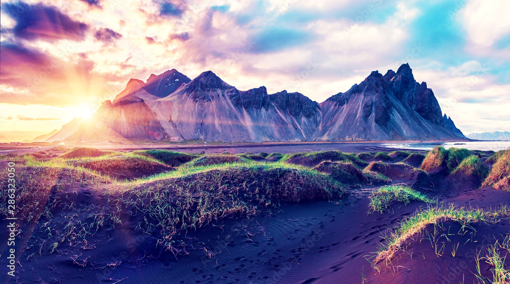 Scenic landscape with most beautiful mountains Vestrahorn on the Stokksnes peninsula and cozy lagoon with green grass on the sand dunes at sunset in Iceland. Exotic countries. Amazing places.