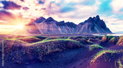 Scenic landscape with most beautiful mountains Vestrahorn on the Stokksnes peninsula and cozy lagoon with green grass on the sand dunes at sunset in Iceland. Exotic countries. Amazing places.