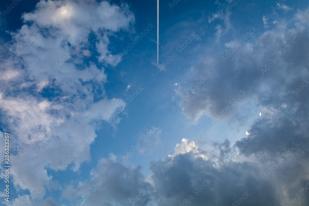 White plane flying with trail in beautiful cloudy sky