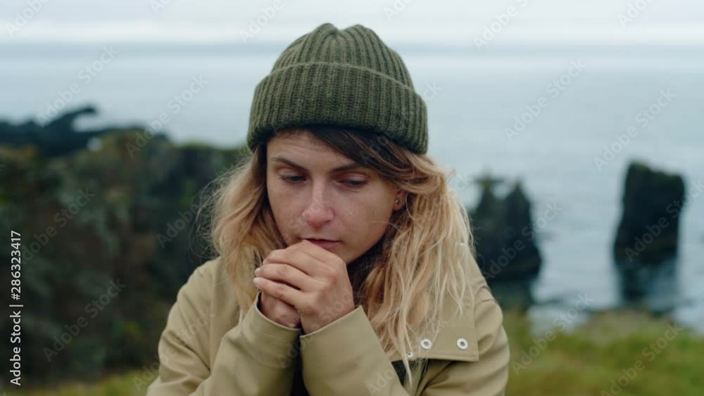 Young woman warms hands with breath in norway Young woman warms hands with breath in norway