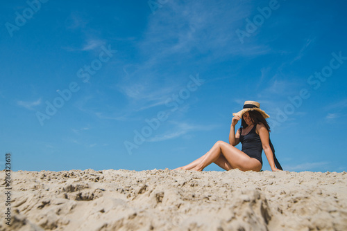 woman at sand beach in black swimsuit blue sky on background