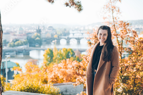 Photography young adult woman in coat. beautiful prague on background