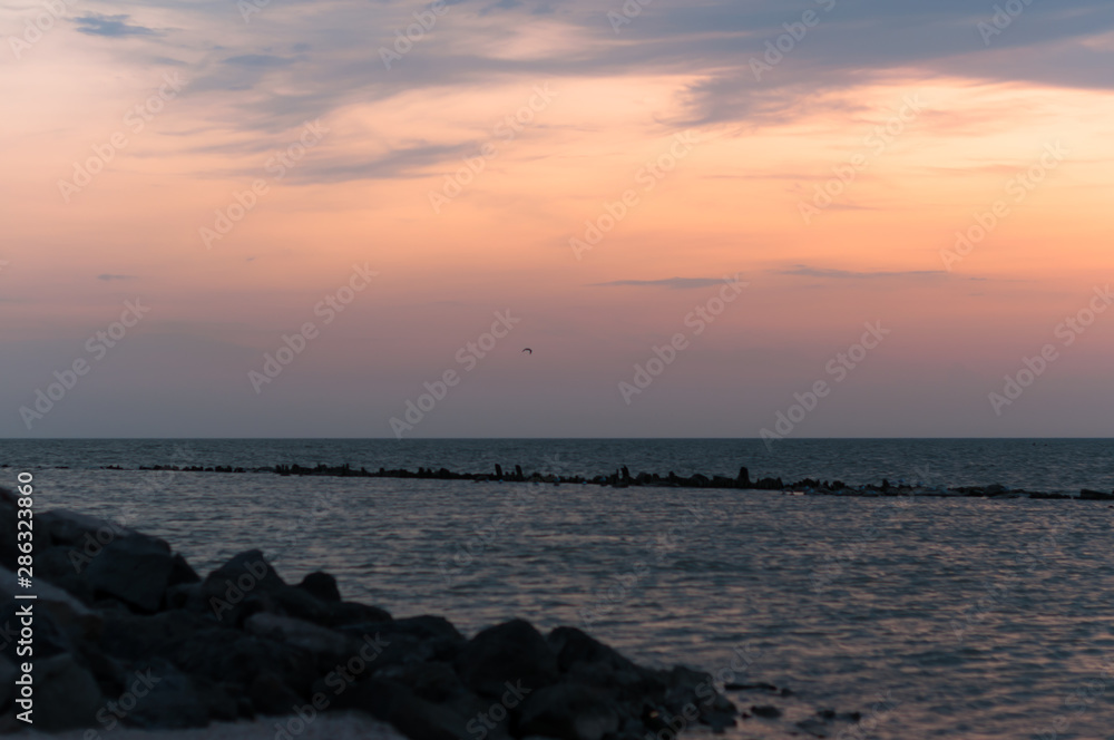 A beautiful sunset on the sea in the summer with a tender pink and orange and lilac color