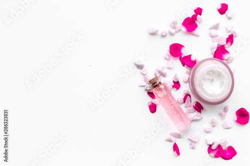 Cosmetics with sea salt and roses decoration on white background top view space for text