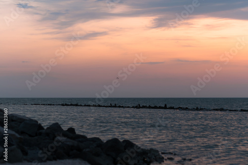 A beautiful sunset on the sea in the summer with a tender pink and orange and lilac color