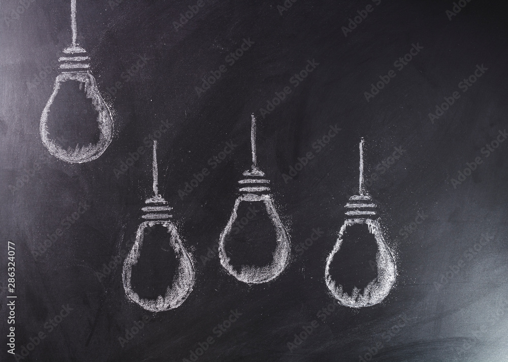 Light bulbs sketched in white chalk with one elevated above the group. Light bulbs sketched in white chalk with one elevated above the group.