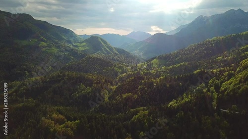 Forward drone shot above slovenian mountains covered in forests, on a cloudy day photo