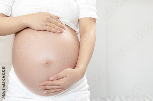 New mom Pregnant woman in white underwear uses hand touch tummy belly with baby. Young woman expecting a baby Stand in the outdoors.