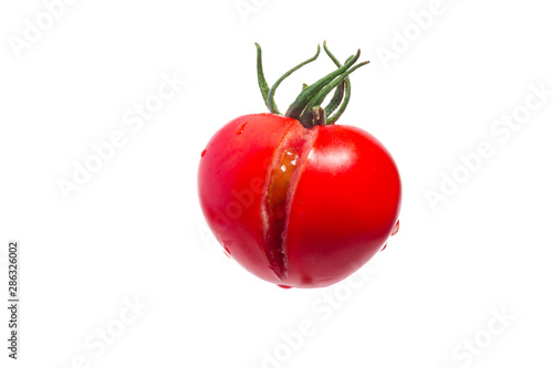 Fotografia Fresh cracked tomato with green peduncle and drops of water isolated on white background
