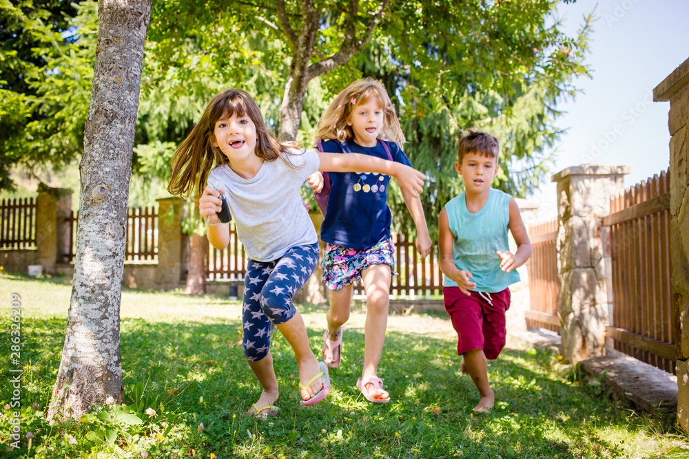 Fototapeta premium Portrait of two girls, sisters and their boy friend running in the park