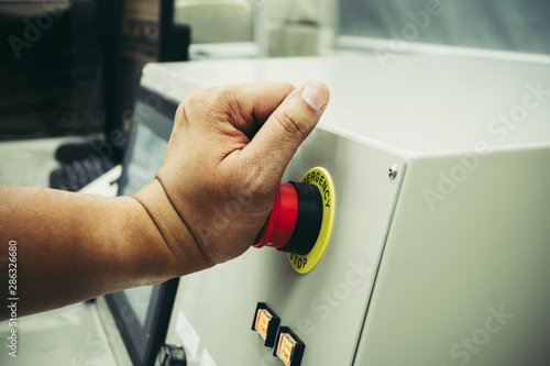 Foto Male Operator use left hand to push emergency button to stop the machine while a