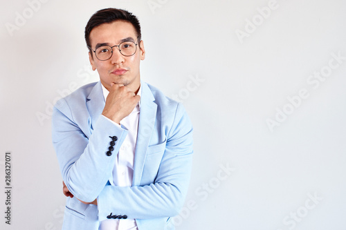 Portrait of smart thinking Kazakh man in glasses dressed in business suit in the office on white background. Asian handsome businessman