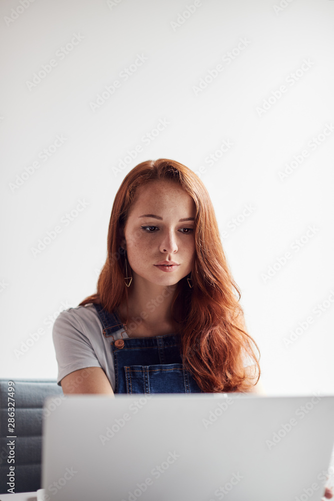 Casually Dressed Young Businesswoman Working On Laptop At Desk In Modern Workplace Casually Dressed Young Businesswoman Working On Laptop At Desk In Modern Workplace