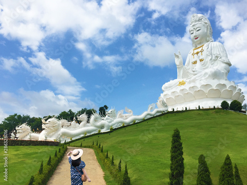 Woman tourist is sightseeing big white Guan Yin statue at Wat (Temple) Huay Pla Kang in Chiang Rai,Thailand. photo