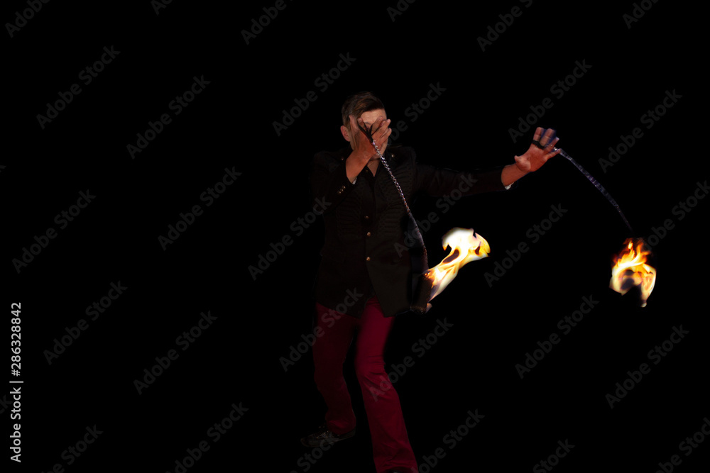 Fototapeta premium Man dominating the fire taking the flames with his chains in motion in Mexico City