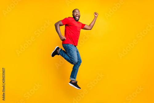 Full length body size side profile photo of casual winning rejoicing overjoyed running black man isolated with yellow background © deagreez