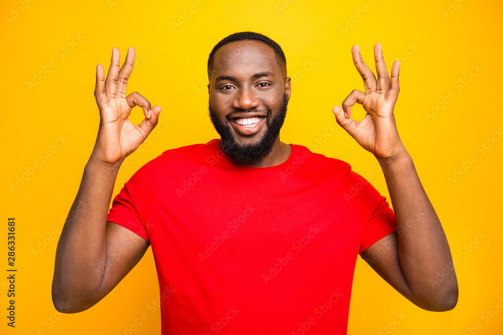 Photo of cheerful rejoicing man having nice deal for you showing you double ok sign friendly smiling while isolated with yellow background Photo of cheerful rejoicing man having nice deal for you showing you double ok sign friendly smiling while isolated with yellow background