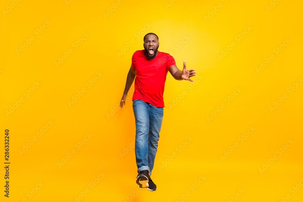 Full length body size photo of angry furious yelling commanding black man wearing jeans denim screaming into camera while isolated with yellow vivid background Full length body size photo of angry furious yelling commanding black man wearing jeans denim screaming into camera while isolated with yellow vivid background