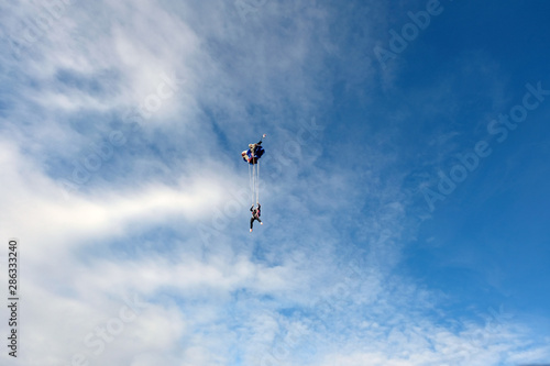 Skydiving. Blonde girl is flying in the blue sky.