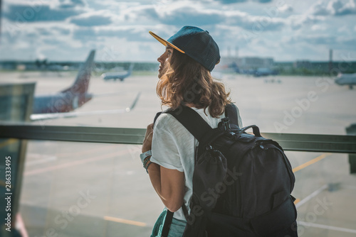 Fotografia young girl traveler with backpack at the airport on the background of the takeof