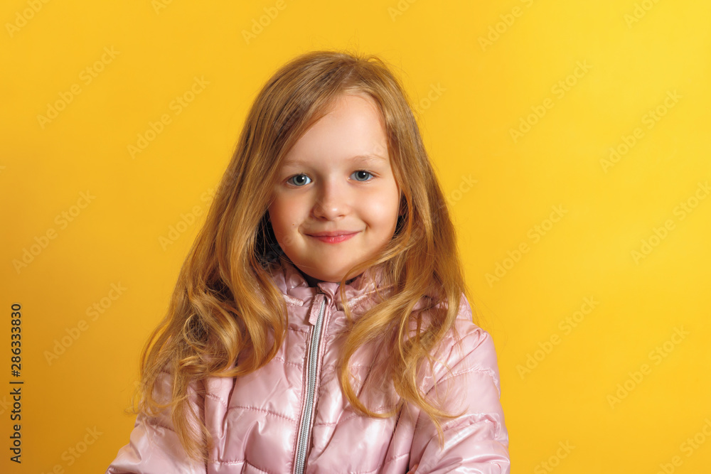 Portrait of a cute little girl in a jacket on a yellow background. Autumn and winter concept. Portrait of a cute little girl in a jacket on a yellow background. Autumn and winter concept.