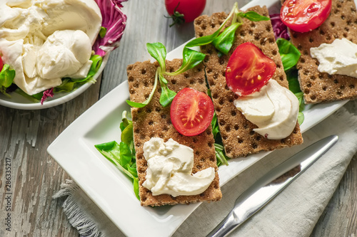 Burato cheese and salad on diet bread. Lollo Rosso lettuce, cress salad and other green herbs. The concept of a healthy diet for the weight loss . Italian dish. Selective focus photo