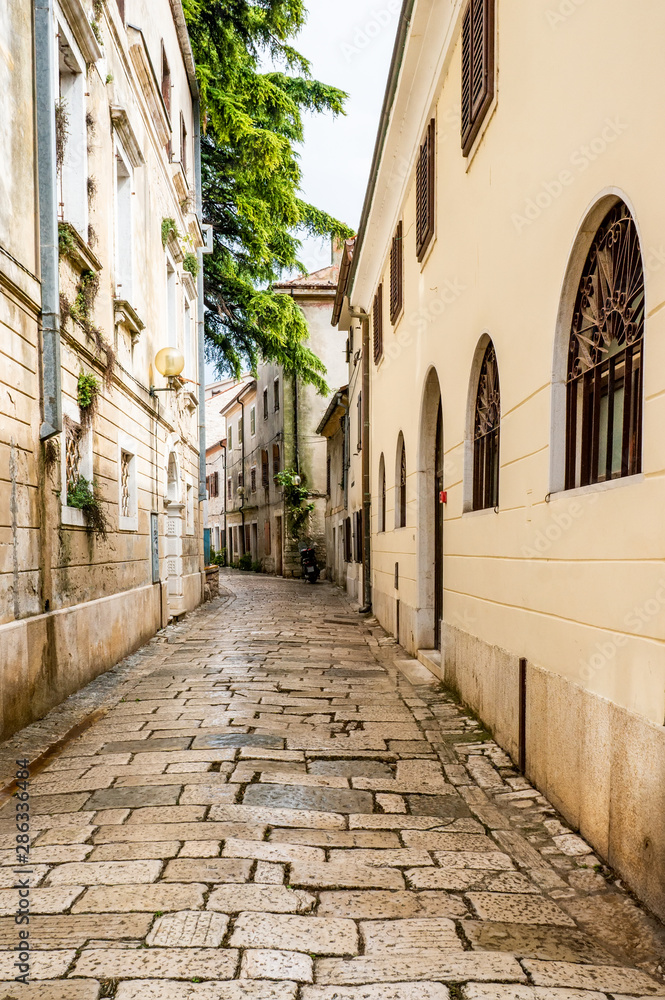 A typical narrow European street with a cobbled pavement. Croatia, the city of Porec A typical narrow European street with a cobbled pavement. Croatia, the city of Porec