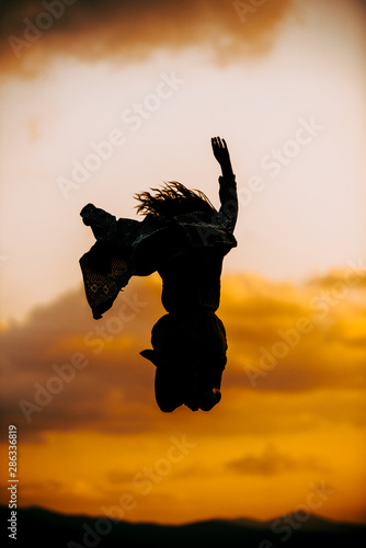 Modern style silhouette woman dancer jumping on sunset
