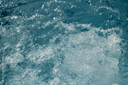 Plan rapproché sur les gouttelettes d'eau de l'écume de la mer dans le ressac des vagues © Noble Nature