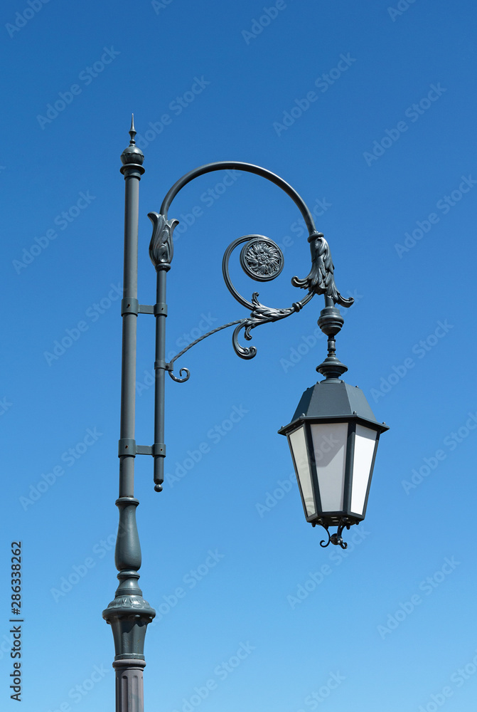 Old metal streetlight on blue sky background