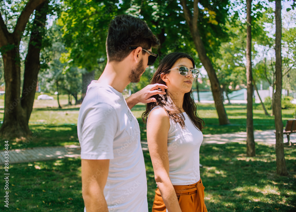 Loving couple walking between trees in the park in sunny day Loving couple walking between trees in the park in sunny day