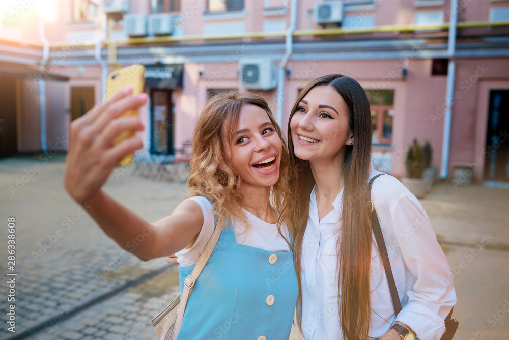 Obraz premium Two girls take a selfie on the phone