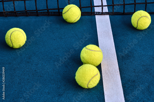 Few tennis balls on the floor at tennis court near net.