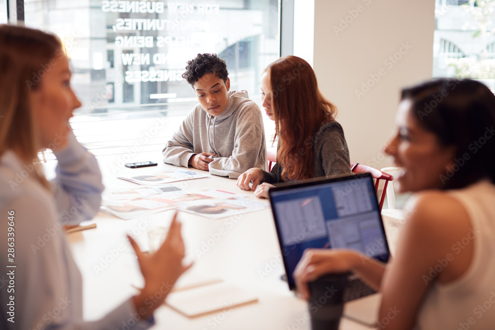 Team Of Young Businesswomen In Meeting Around Table In Modern Workspace