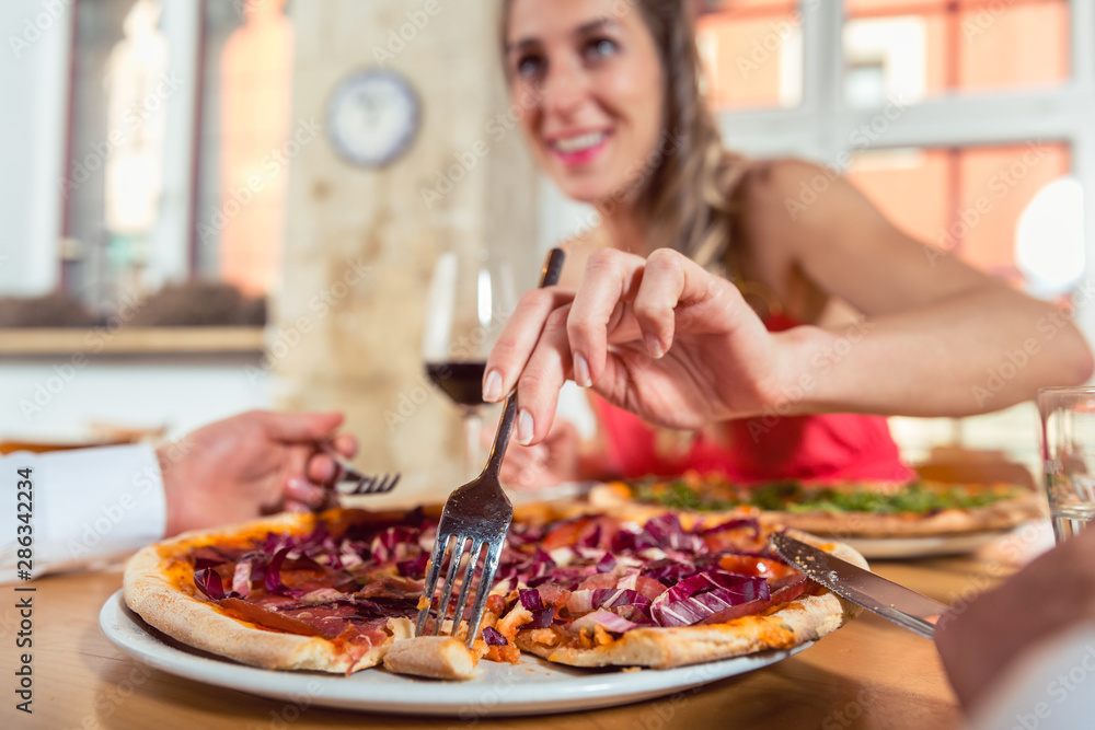 Woman eating pizza from her boyfriend's plate