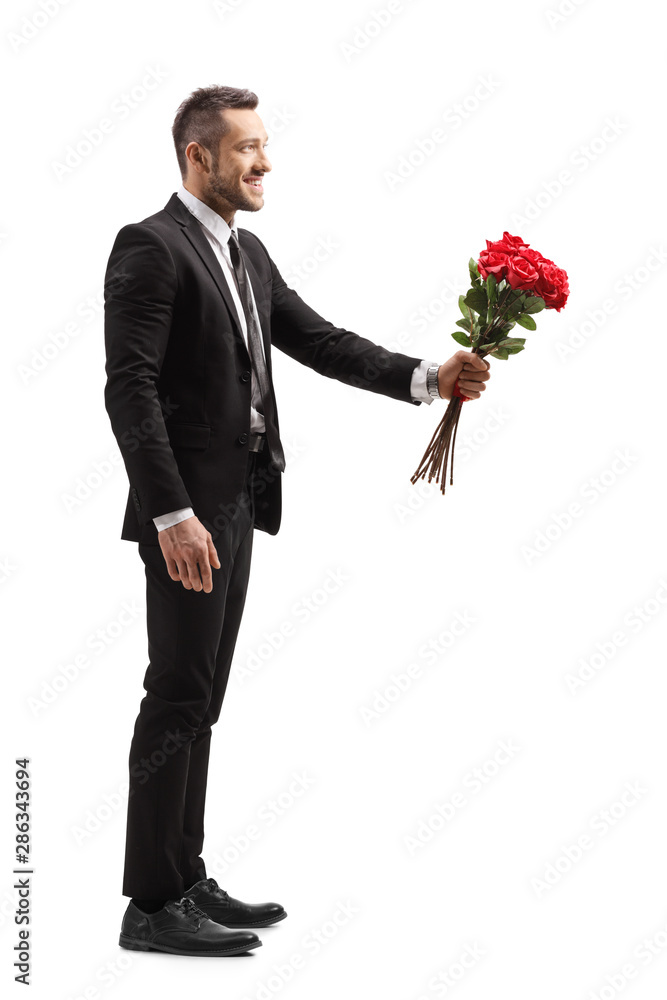 Young elegant man smiling and giving a bunch of red roses Young elegant man smiling and giving a bunch of red roses