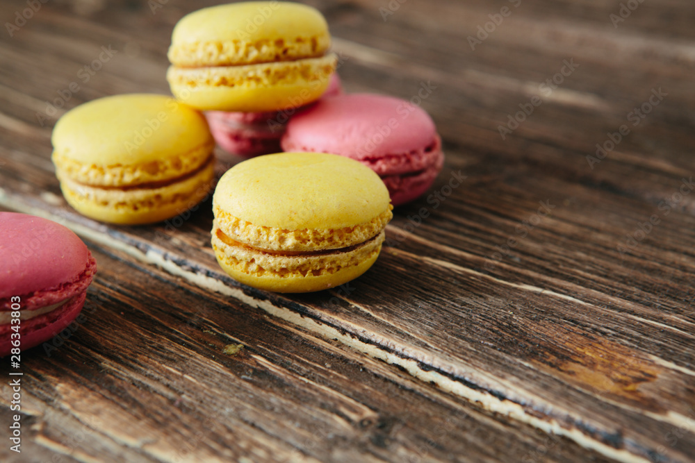 Sweet colorful French macaroon cookies dessert on brown wooden table Sweet colorful French macaroon cookies dessert on brown wooden table