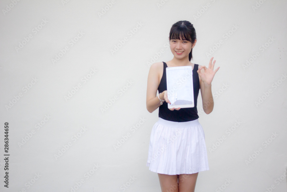 Portrait of thai adult beautiful girl black shirt white skirt show her tablet. Portrait of thai adult beautiful girl black shirt white skirt show her tablet.