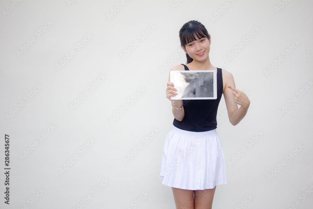 Portrait of thai adult beautiful girl black shirt white skirt show her tablet.
