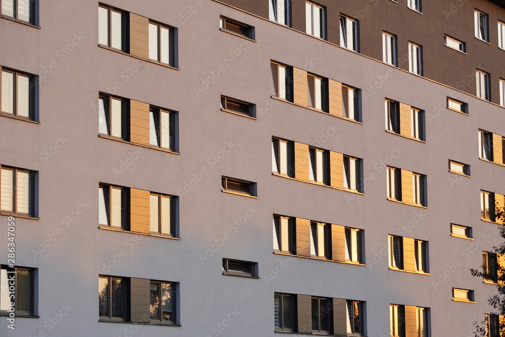 Windows reflecting sunlight at sunset in a modern multi-storey building.