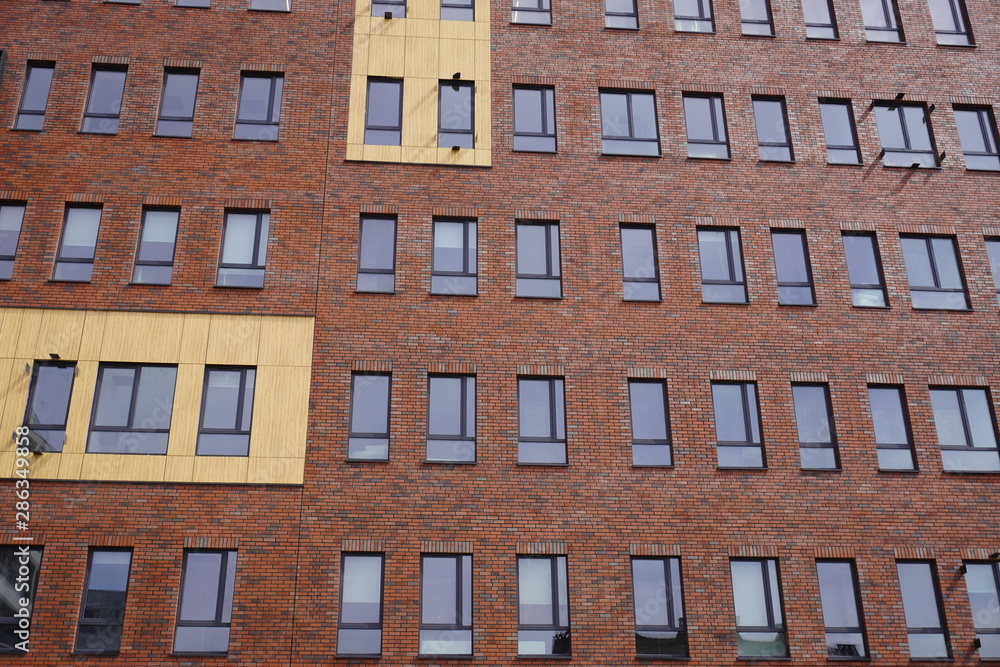 the facade of the building is Burgundy with symmetrical narrow window openings the facade of the building is Burgundy with symmetrical narrow window openings