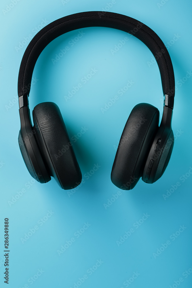Black bluetooth headphones on a blue background top view. In-Ear Headphones for DJs Black bluetooth headphones on a blue background top view. In-Ear Headphones for DJs
