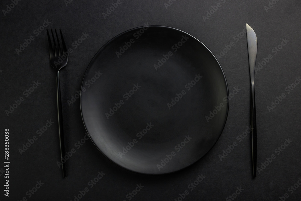 Black setting: plates, linen napkin and silverware on blfck background. Top view. Black setting: plates, linen napkin and silverware on blfck background. Top view.