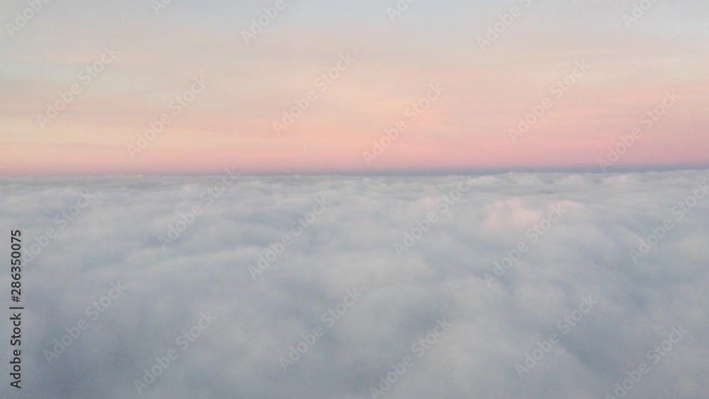 The plane wing is flying when viewed from the window. Sun horizon airplane wing. View from airplane window with blue sky and white clouds The plane wing is flying when viewed from the window. Sun horizon airplane wing. View from airplane window with blue sky and white clouds
