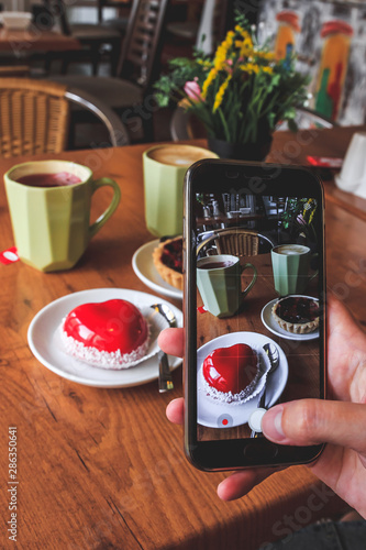 Close up of female hand's taking photo of cups and cakes