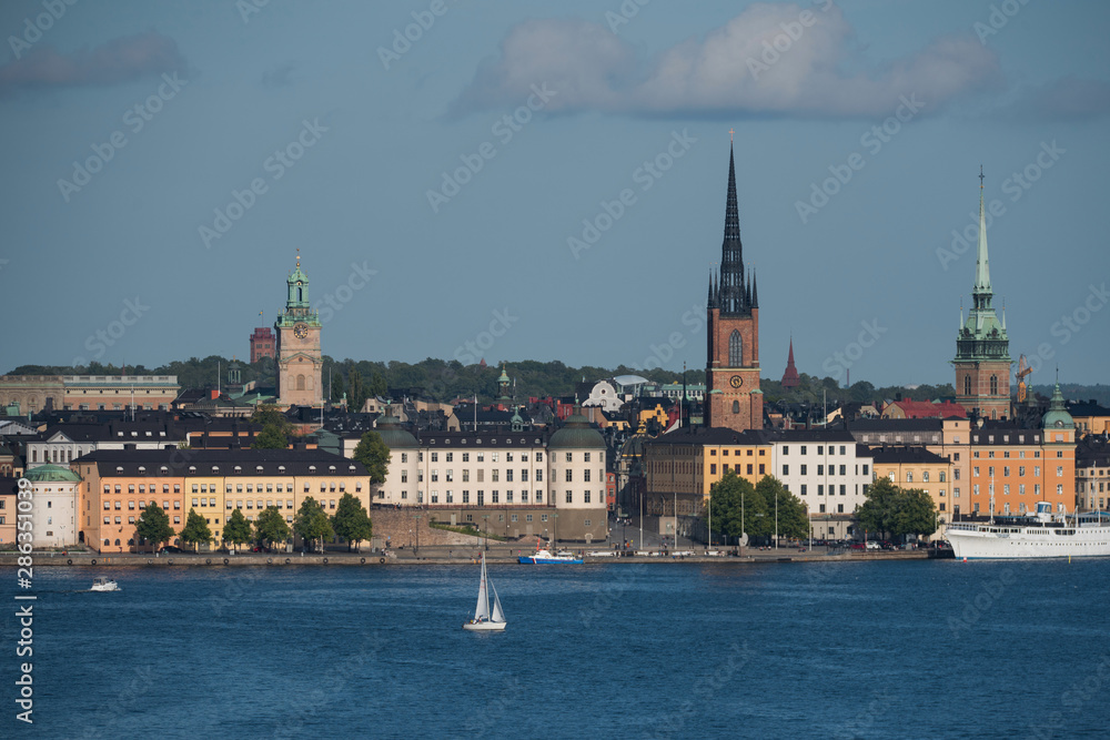 Fototapeta premium Stockholm buildings at the bay Riddarfjärden between the district Södermalm, Kunsholmen, Gamla Stan and Riddarholmen at sunset with a low sun and fogg torning up in the archipelago